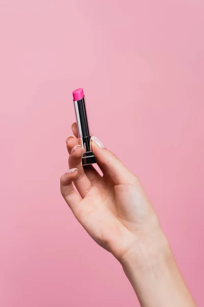 Vista recortada de la mujer sosteniendo lápiz labial en la mano aislado en rosa - foto de stock