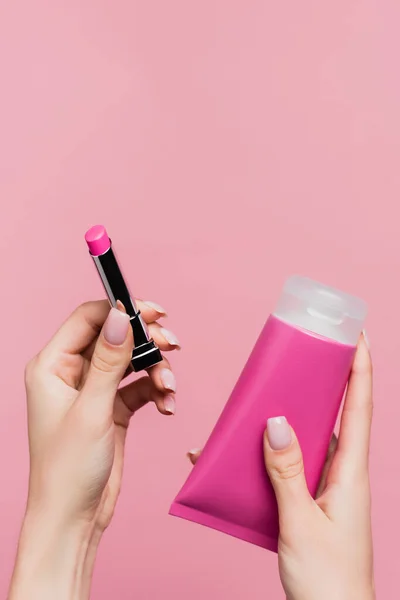 Abgeschnittene Ansicht einer Frau mit Lippenstift und Tube mit Körpercreme isoliert auf rosa — Stockfoto