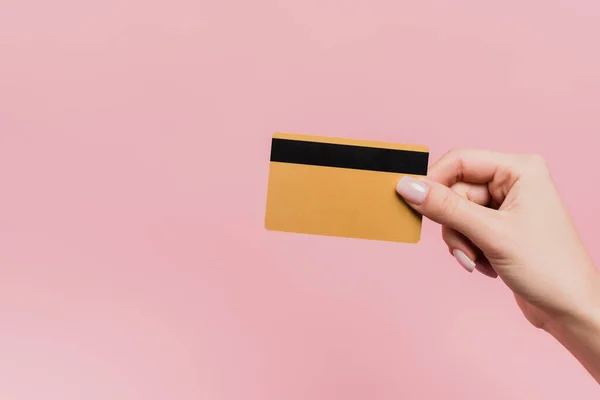 Частичный взгляд женщины, держащей кредитную карту в руке изолированы на розовый — стоковое фото