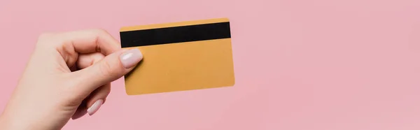 Partial view of woman holding credit card in hand isolated on pink, banner — Stock Photo