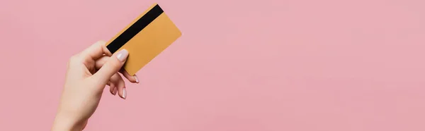 Partial view of woman holding credit card isolated on pink, banner — Stock Photo