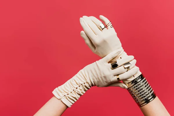 Vista parcial de mujer en guantes con anillos y brazalete aislado en rojo - foto de stock