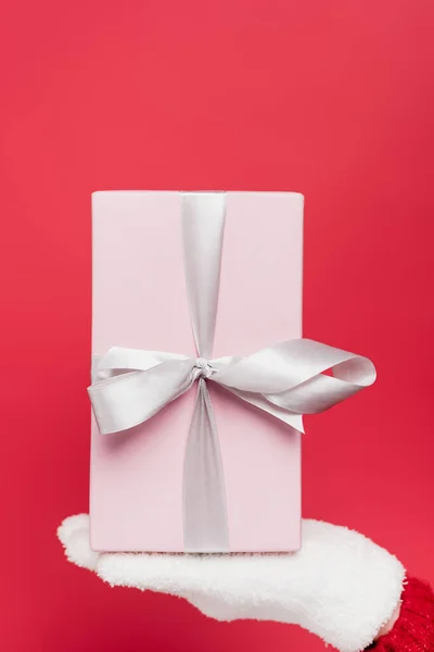 Cropped view of woman in white glove holding pink present isolated on red — Stock Photo