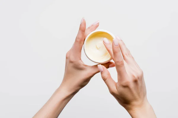 Vista dall'alto della donna che tiene contenitore con crema cosmetica isolata su bianco — Foto stock