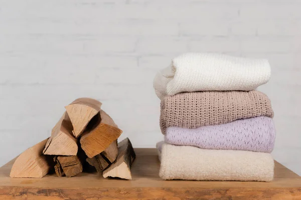 Grumes en bois près de chandails tricotés chauds sur table sur fond blanc — Photo de stock