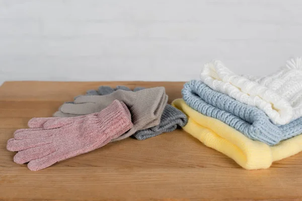 Chapeaux et gants tricotés confortables sur une table en bois sur fond blanc — Photo de stock