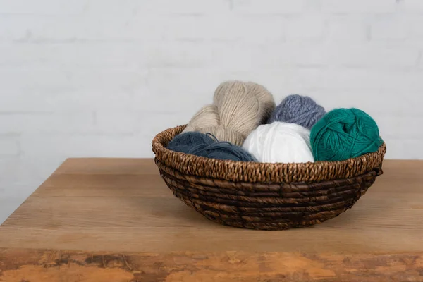 Bolas de hilo de colores en cesta sobre mesa de madera sobre fondo blanco — Stock Photo