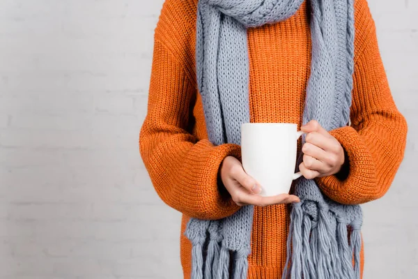 Vista ritagliata della donna in maglia usura tenendo tazza su sfondo bianco — Foto stock