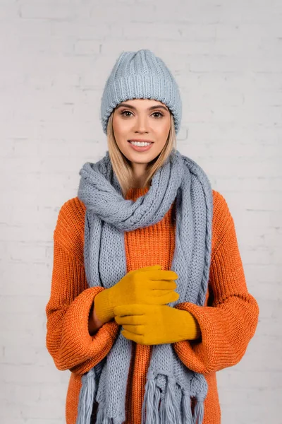 Mujer joven con sombrero caliente, suéter de punto y guantes mirando a la cámara sobre fondo blanco - foto de stock