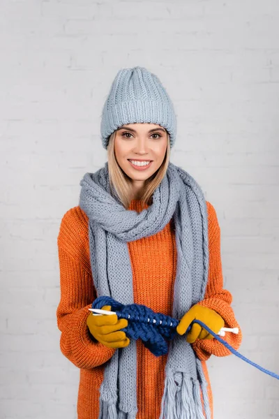 Mujer sonriente en ropa de abrigo tejiendo sobre fondo blanco - foto de stock
