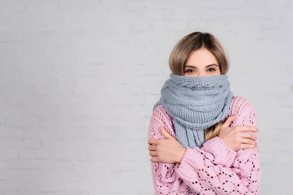 Жінка в теплому шарфі і светрі страждає від холоду на білому тлі — стокове фото