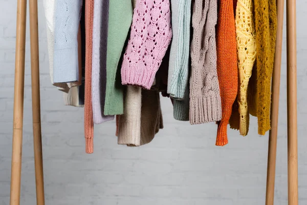 Вязаные свитера на деревянной вешалке на белом фоне — стоковое фото