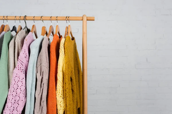 Wooden hanger rack with warm sweaters on white background — Stock Photo