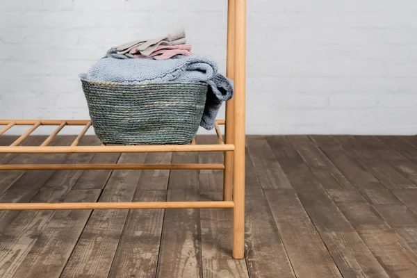 Basket with knitted sweater and gloves on hanger rack — Stock Photo