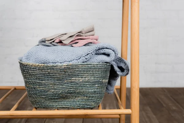 Handschuhe und warmer Strickpullover im Korb auf Kleiderbügel — Stockfoto