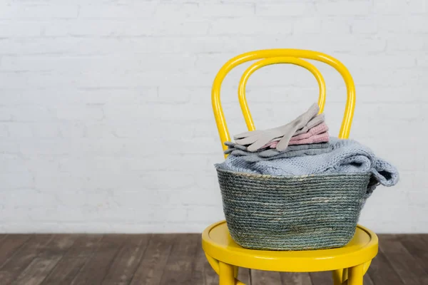 Soft gloves and sweater in basket on chair at home — Stock Photo