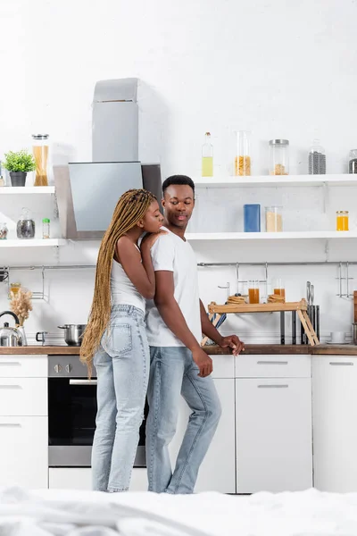 Afro-americana mujer abrazando novio cerca de desayuno en bandeja en cocina - foto de stock