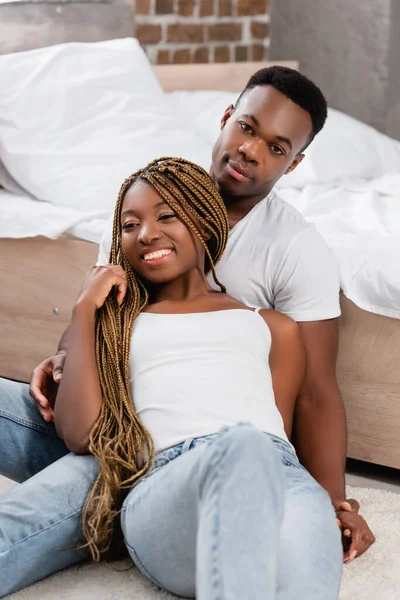 Sorrindo Africano americano mulher sentada perto namorado no chão no quarto — Fotografia de Stock