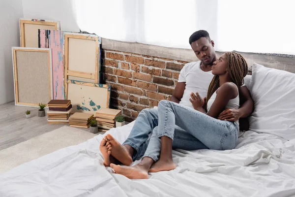 Joven pareja afroamericana abrazándose en la cama en casa - foto de stock