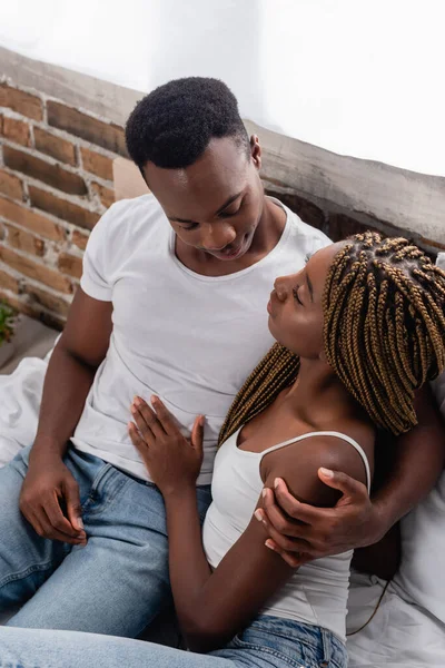 Вид сверху на африканскую американскую пару, обнимающуюся на кровати — стоковое фото