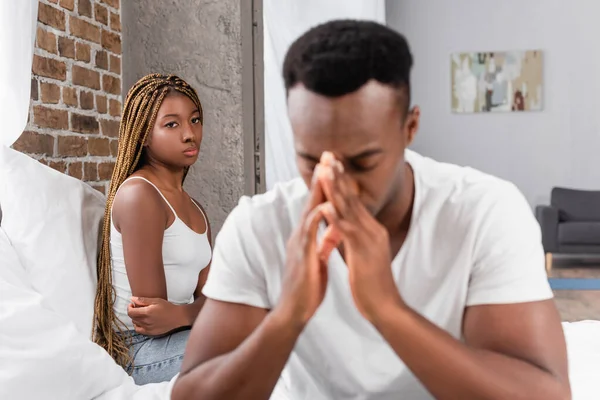 African american woman looking at upset boyfriend on blurred foreground in bedroom — Stock Photo