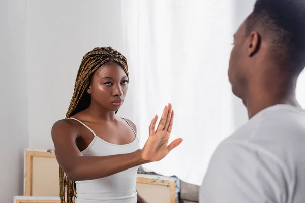 African american woman showing stop gesture near boyfriend on blurred foreground at home — Stock Photo
