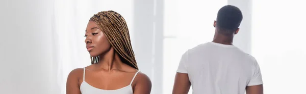 Femme afro-américaine debout près de petit ami sur fond flou à la maison, bannière — Photo de stock