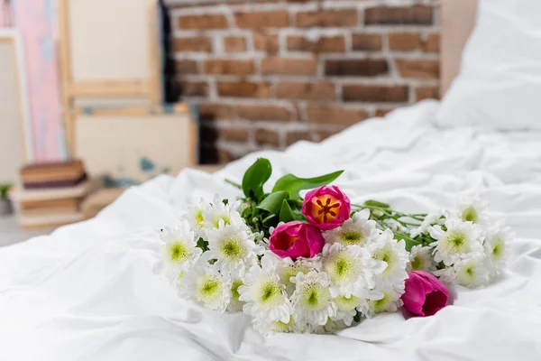 Crisântemos e tulipas em buquê em roupa de cama branca — Fotografia de Stock