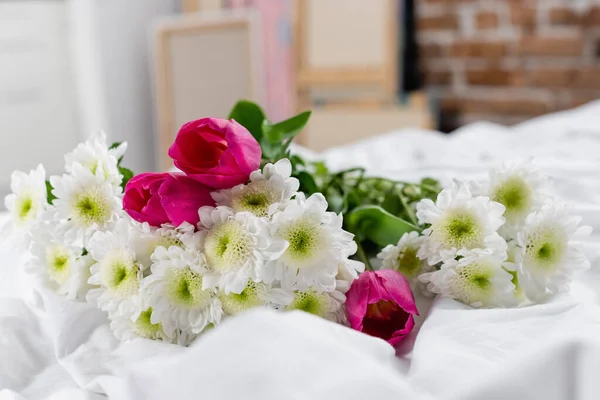 Chrysanthèmes et tulipes sur literie blanche au premier plan flou — Photo de stock