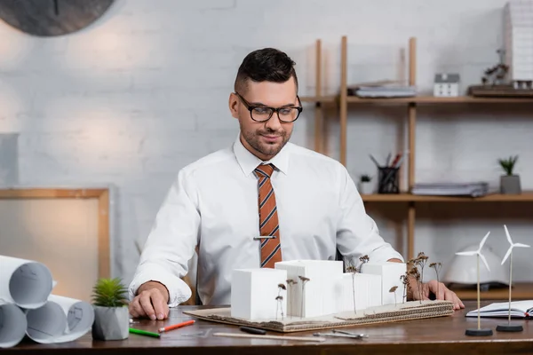 Erfolgreicher Architekt betrachtet Konstruktionsmakette am Arbeitsplatz — Stockfoto