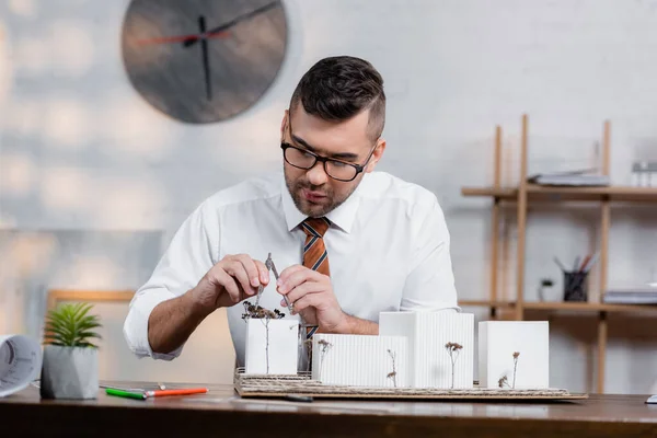 Concentrated architect measuring house model with divider — Stock Photo