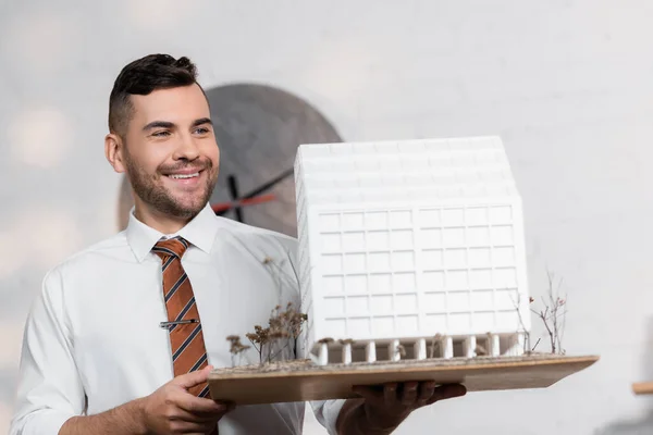 Happy architect holding house model in architectural agency — Stock Photo