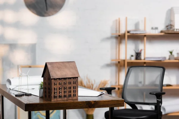 Maquette de bâtiment et modèles d'éoliennes sur bureau près d'une chaise de bureau — Photo de stock