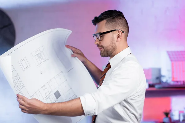 Архітектор в окулярах дивиться на план в архітектурному агентстві — стокове фото
