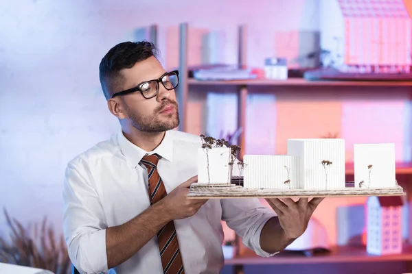 Serious architect holding constructions models in architectural agency — Stock Photo