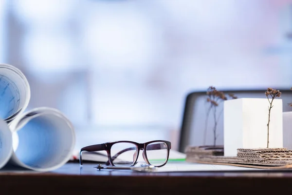 Foyer sélectif des lunettes près des plans roulés sur le bureau — Photo de stock