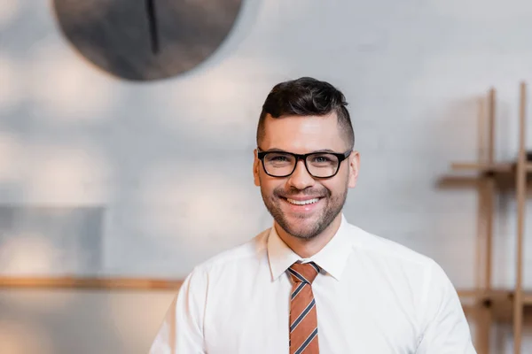 Happy architect in eyeglasses smiling at camera in architectural agency — Stock Photo