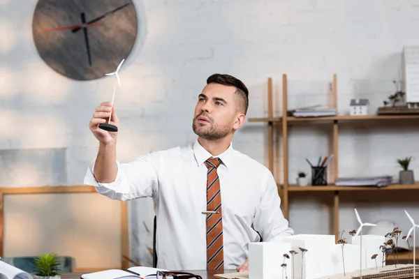 Architekt hält Modell eines Windgenerators in der Nähe eines architektonischen Projekts am Arbeitsplatz — Stockfoto