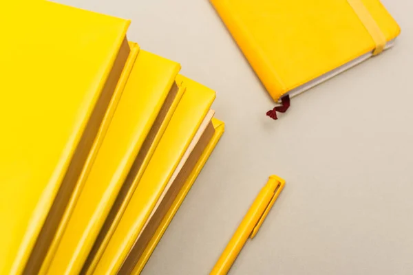 Vista superior de cuadernos amarillos cerca de pluma aislada en gris - foto de stock