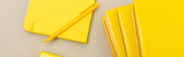 Top view of yellow notebooks near pen isolated on grey, banner — Stock Photo