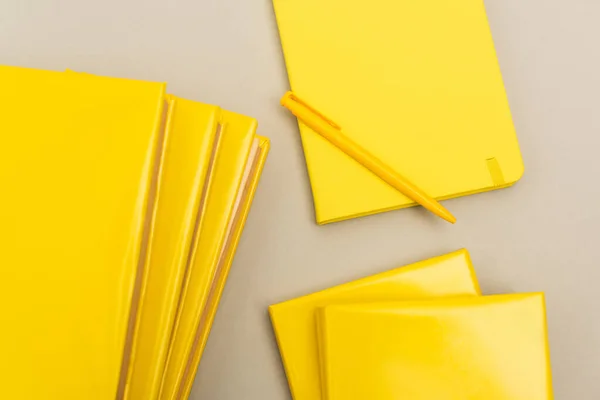 Вид зверху на жовті блокноти біля ручки ізольовані на сірому — стокове фото