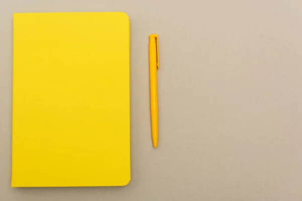 Vista superior del cuaderno amarillo cerca de la pluma aislada en gris - foto de stock