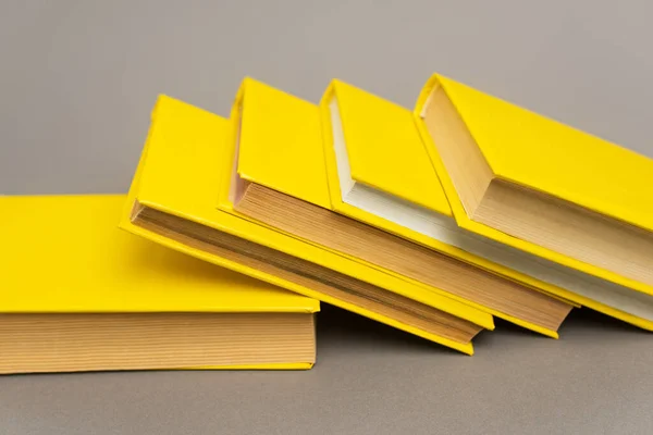 Stacked yellow notebooks and books on grey — Stock Photo