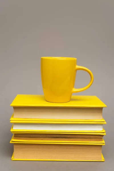 Mug on stack of yellow notebooks isolated on grey — Stock Photo