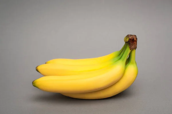 Bananes mûres jaunes sur fond gris — Photo de stock