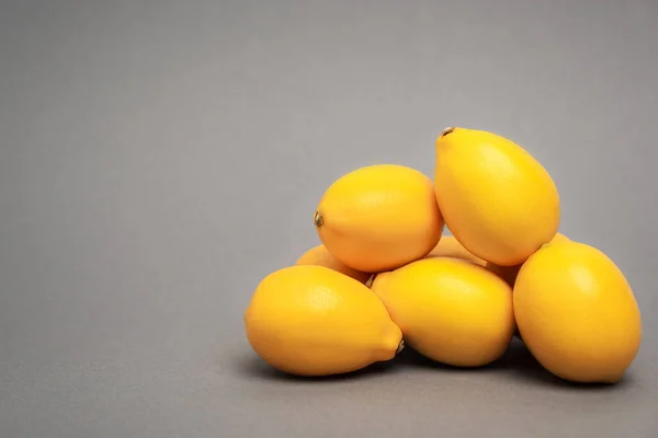 Reife und gelbe Zitronen auf grauem Hintergrund — Stockfoto