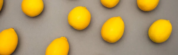 Vista de ángulo alto de limones frescos y amarillos sobre fondo gris, bandera - foto de stock