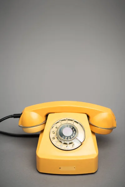 Yellow and retro telephone on grey background — Stock Photo