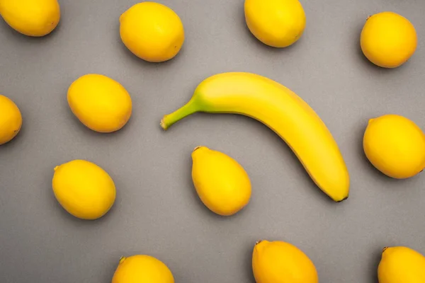 Draufsicht auf reife gelbe Banane und Zitronen auf grauem Hintergrund — Stockfoto