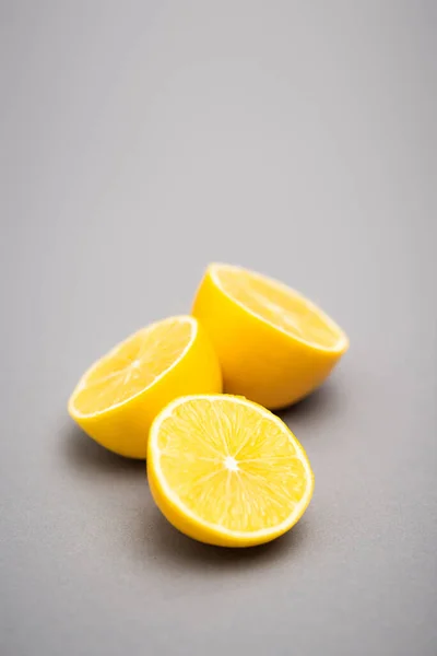 Trois moitiés de citrons juteux sur fond gris — Photo de stock